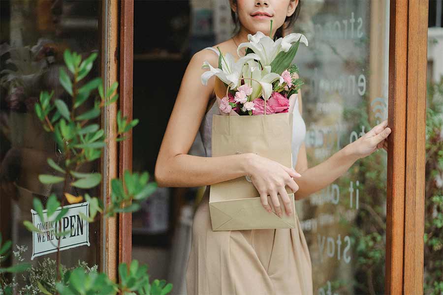 Seasonal Cash flow image of flady leaving shop after purchasing flowers. Photo by Amina Filkins: https://www.pexels.com/photo/crop-young-woman-leaving-floral-shop-with-tender-bouquet-5414055/