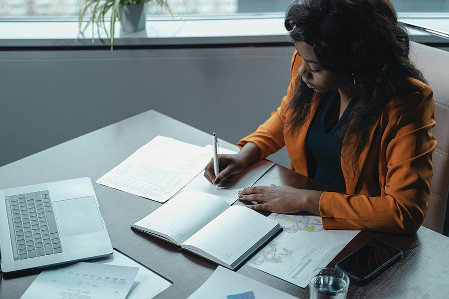 What is a finance manager blog image. With a woman sitting at a desk with papers and a laptop out. Photo by Tima Miroshnichenko: https://www.pexels.com/photo/a-woman-sitting-at-the-table-5717306/